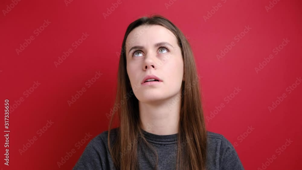 Depressed young woman showing finger gun gesture at her temple, dressed in grey t-shirt, isolated over red background. Negative human emotions and feelings concept Depressed young woman showing finger gun gesture at her temple, dressed in grey t-shirt, isolated over red background. Negative human emotions and feelings concept