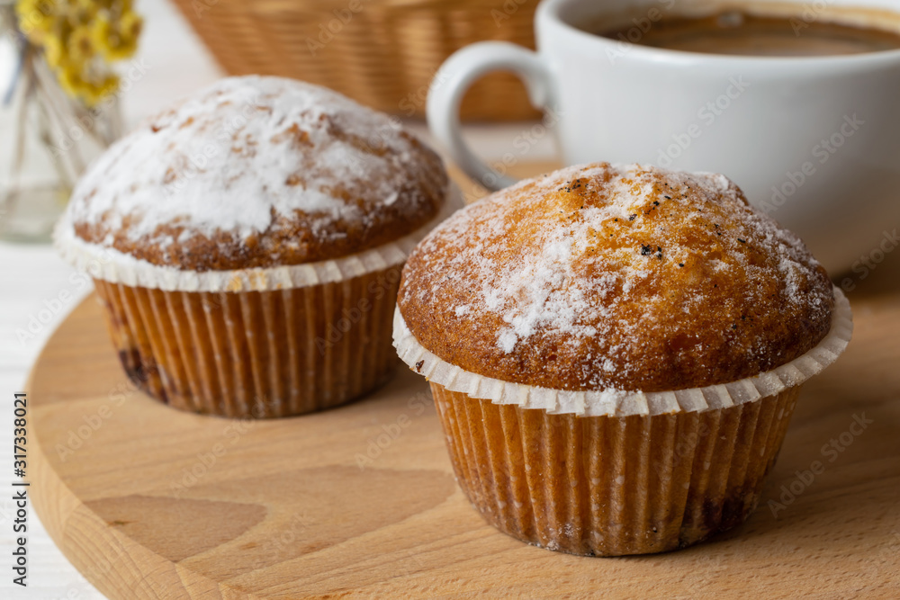 Fresh homemade muffins with sugar powder and a cup of coffee. Close up background Fresh homemade muffins with sugar powder and a cup of coffee. Close up background