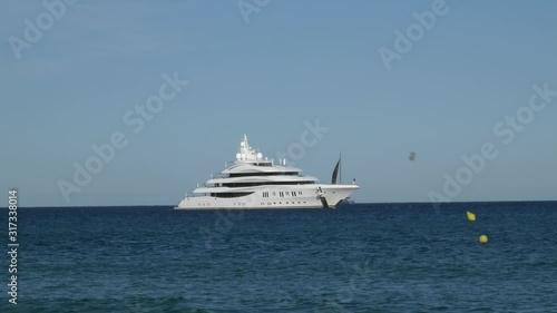 Weiße luxus Yacht mit einem Segelboot mit schwarzen Segeln auf wunderschönem blauem Wasser am Strand von Saint Tropez in Frankreich 
