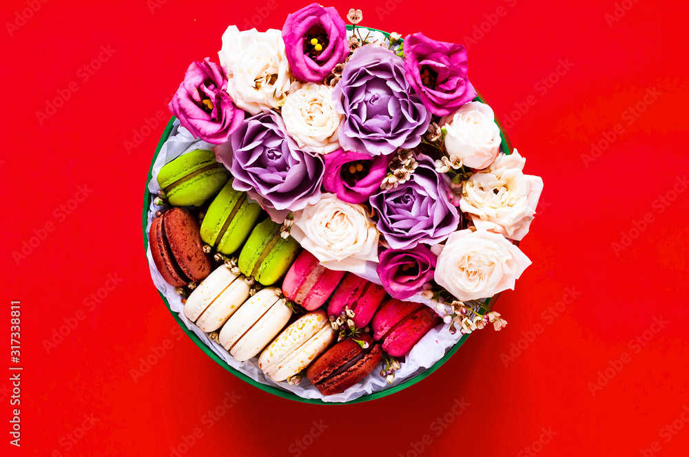 Festive concept from rosebuds in full bloom and Multicolored Macaroons on red background. Valentines Day. Template mock up of greeting card or text design. Close-up