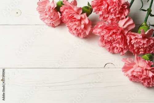 Pink carnation flowers on white wood.