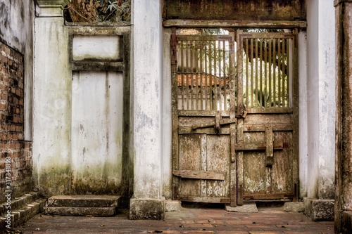 Ancient wooden gate in an old building with weathered walls