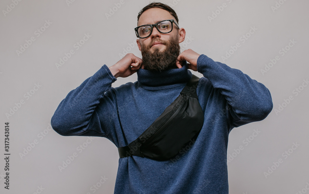 Handsome hipster guy with beard wearing blue blank sweatshirt with waist bag. Mockup for print