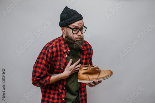 Hipster man holding dirty stinky shoe isolated on white background