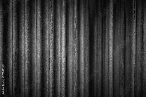 Close-up of an aged, dirty and corrugated wall. Dark high resolution abstract full frame textured background in black and white.