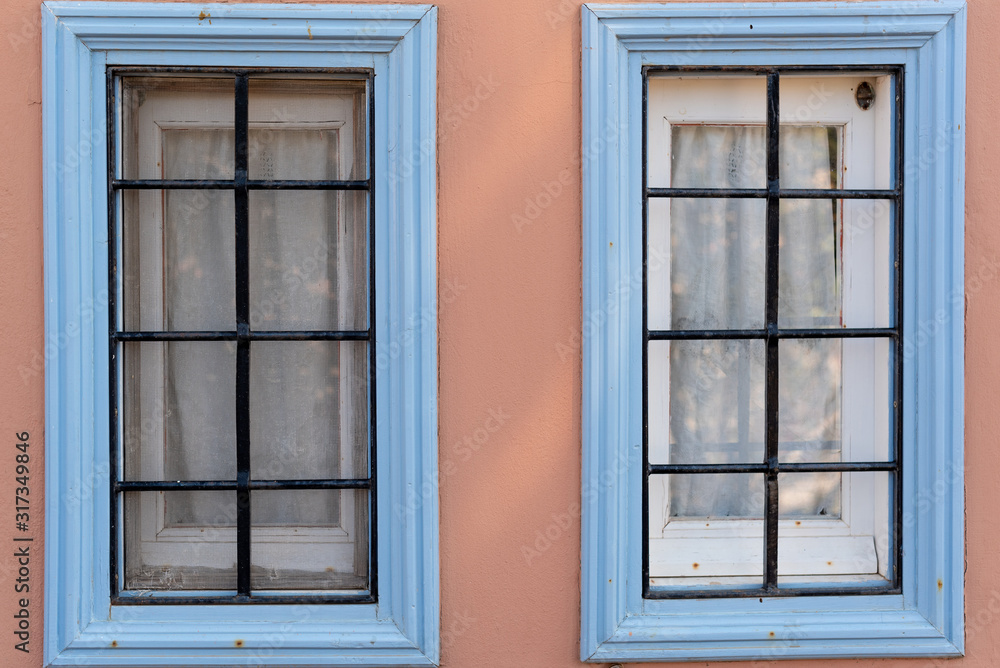 Two similar old wooden windows on the wall. The traditional colorful design in island Symi in Greece. 