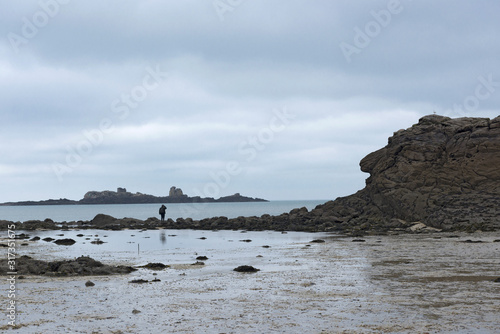France. Bretagne. Ile et Vilaine. Une silhouette au bord de l'océan sur des rochers à marée basse. A silhouette at the edge of the ocean on rocks at low tide.