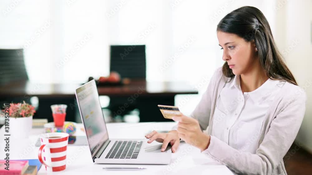 Young woman shopping online. Attractive woman using a credit card to buy on the internet. Dolly shot. Technology. Young woman shopping online. Attractive woman using a credit card to buy on the internet. Dolly shot. Technology.