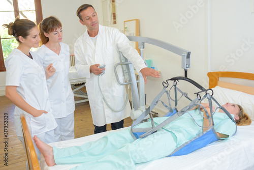 female patient being hoisted from bed