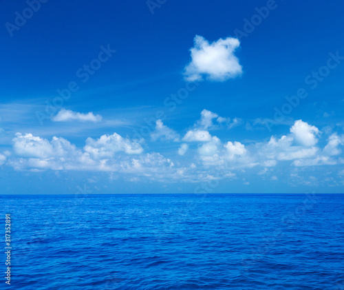 Sea and blue sky. Blue sea water and sky with white fluffy clouds. Horizontal background of blue sea. Tropical landscape