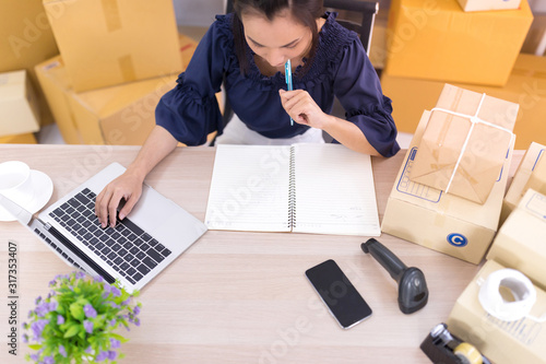 Top view, Asian women who are SME online shopping operators and are writing lists on notebooks SME online shopping business entrepreneurs or independent work concept