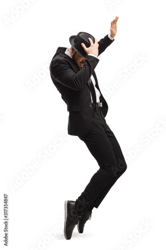 Photography Young man in a suit dancing and holding his hat