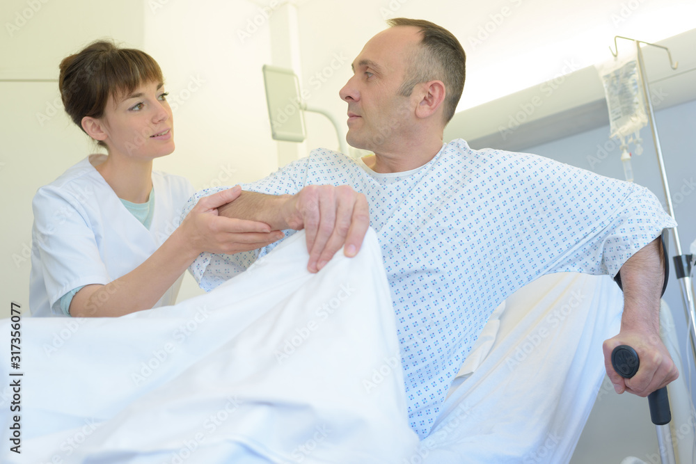 Fototapeta premium nurse helping injured man out of bed