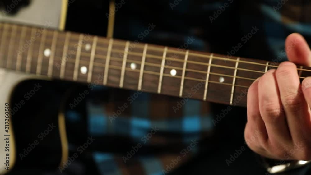 Hands playing on acoustic guitar strings keeping the rhythm of a slow romantic melody, close up, pan shot