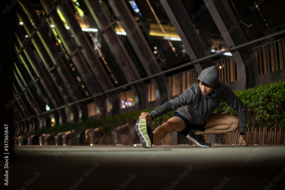 Young man warming up before night run Young man warming up before night run