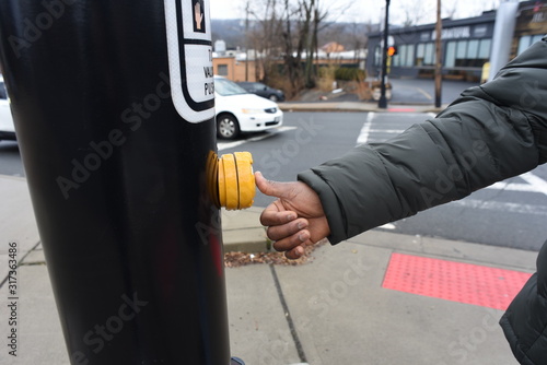 African American pressing the cross button. safety first. A black hand pressing a knob. A cute man trying to cross the road. A man waiting the walk on the zebra crossing photo