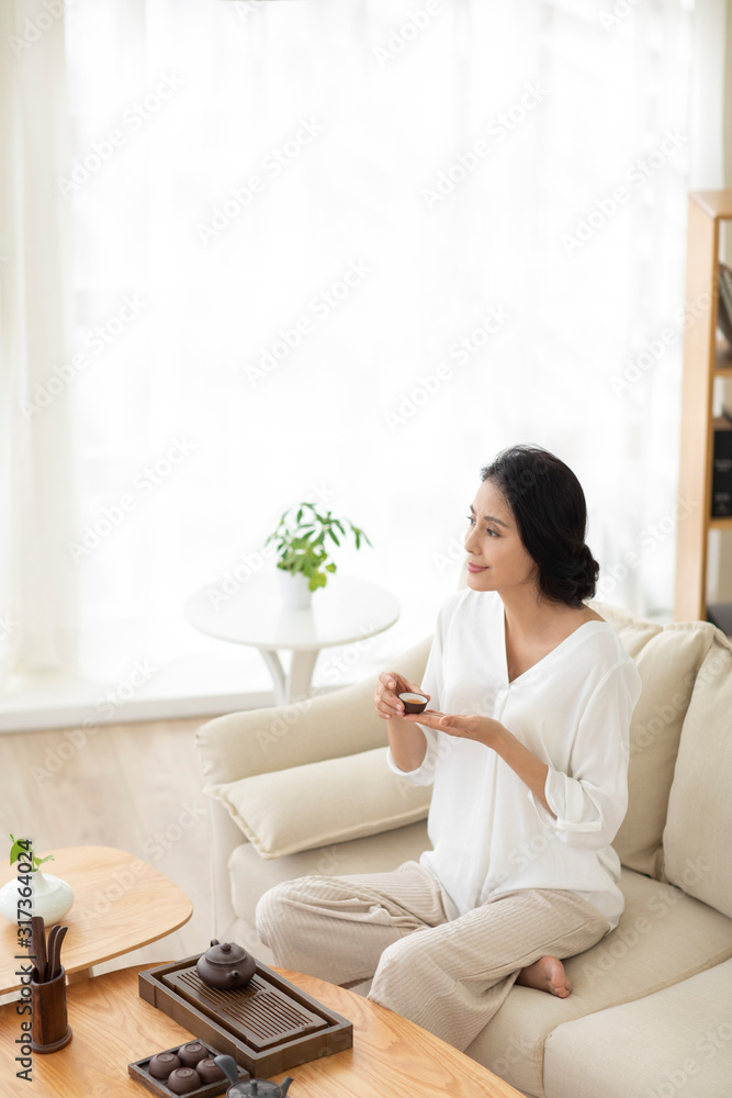 Mature woman drinking tea in living room Mature woman drinking tea in living room