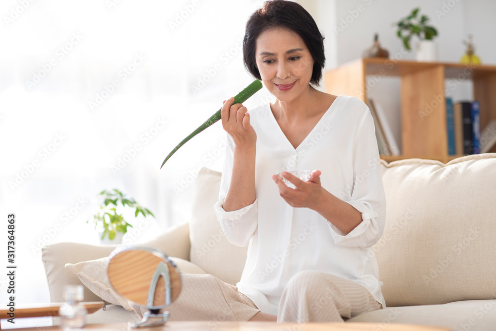 Mature woman applying aloe vera at home Mature woman applying aloe vera at home