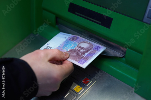 Male hand while withdrawing 50 Ukrainian hryvnia from an ATM. The depreciation of the national currency, the hryvnia.