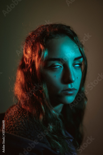 Focused mystique young long haired woman rolling eyes in studio on dark background photo