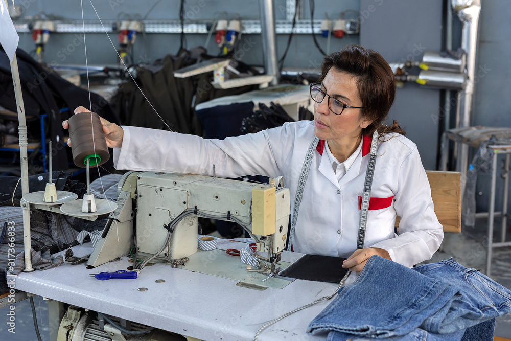 Working woman hands in textile factory sewing on industrial sewing ...