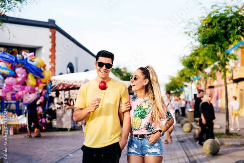 Content couple having fun walking on street in fair