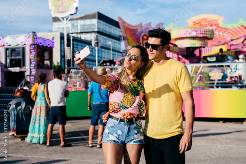 Joyful woman taking selfie with boyfriend on fair photo