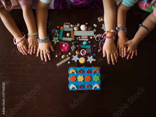 From above anonymous girls in bracelets playing with collection of various knick knacks on table at home photo