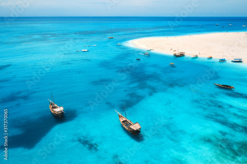 Aerial view of fishing boats on tropical sea coast with transparent blue water and sandy beach at sunny day. Summer holiday. Indian Ocean in Zanzibar, Africa. Landscape with boat, white sand. Top view © den-belitsky