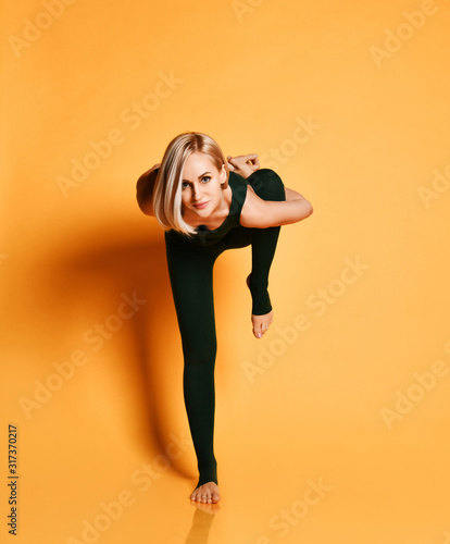 Blonde athletic girl trainer doing yoga pose asana stretches in sport fitness gym club in green sportswear on yellow  © Dmitry Lobanov
