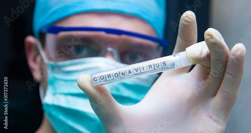 A scientist holds in his hand a test tube with the virus coronavirus. photo
