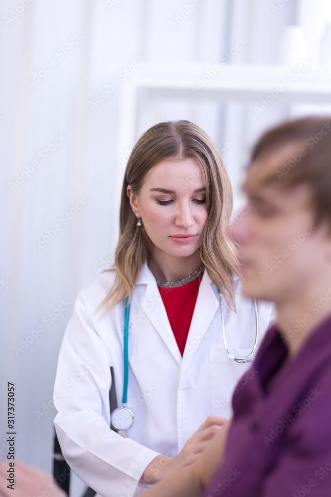 Portrait Of Female Doctor Wearing White Coat is Examining male Patient in the hospital. Portrait Of Female Doctor Wearing White Coat is Examining male Patient in the hospital.