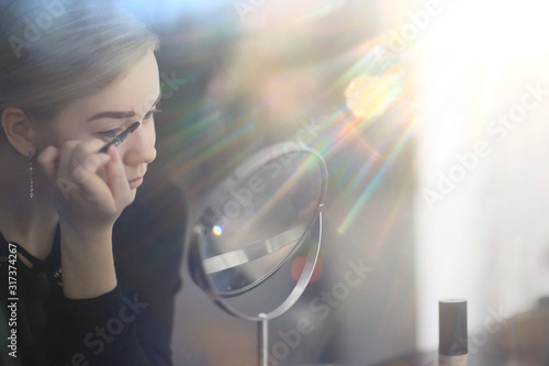 makeup girl at home by the mirror, young blonde adult model, face cosmetics concept