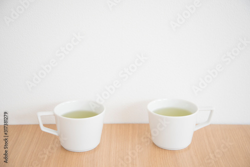 シンプルなマグカップに入れた緑茶 ２つ 2人 ２人 ふたり 二人 余白 ホワイトスペース 文字スペース コピースペース 空白 背景 背景素材 グラフィック背景 グラフィック素材 木目 木 テーブル 机 上