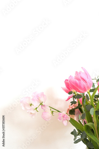 シンプルな花瓶とピンク系の花　ピンク系の花とグリーン　部屋　白壁　白背景　室内　屋内　自然光　余白　ホワイトスペース　コピースペース　文字スペース　縦　背景素材　背景　グラフィック素材　　白　緑　ピンク　春　季節　スイートピー