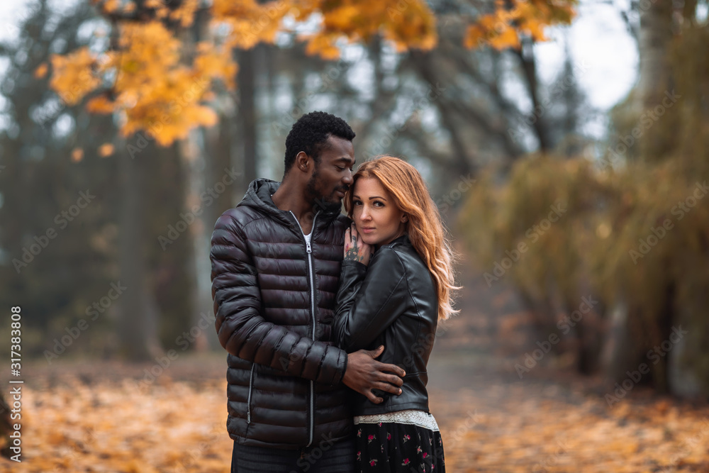 Interracial couple posing in blurry autumn park background Interracial couple posing in blurry autumn park background