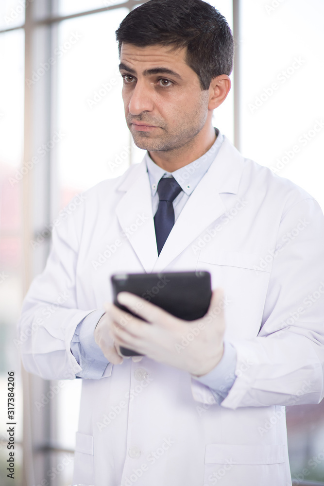 A male scientist wore a white coat and was standing at the edge of a window lab and using a telephone to search for information. A male scientist wore a white coat and was standing at the edge of a window lab and using a telephone to search for information.