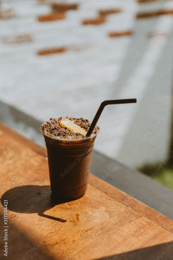 Iced chocolates topped with chocolate flakes and oranges on a wooden table in this café Iced chocolates topped with chocolate flakes and oranges on a wooden table in this café