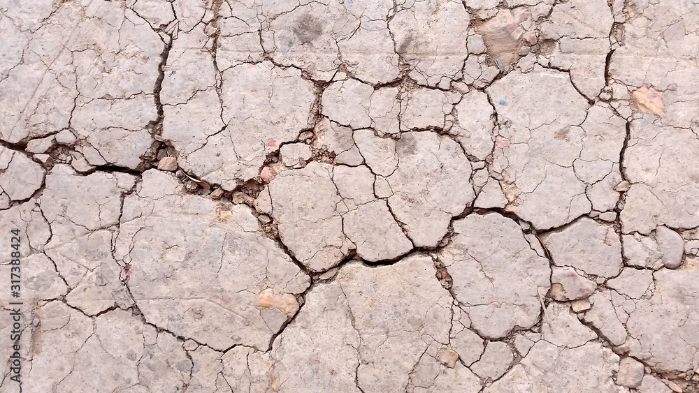 Fototapeta premium Broken land or close-up arid ground. Photo of land in the desert. Cracked land crust. Hard shadows and cracked ground from top view. Royalty free stock photograph.