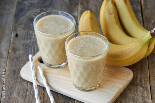 Two glasses of banana smoothie on a wooden board