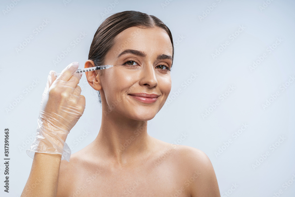 Charming Caucasian girl is ready for beauty procedures against light background