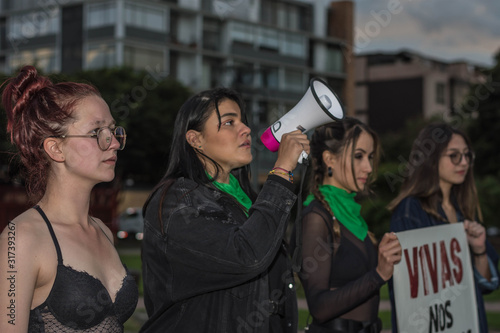Group of feminist activists holding placard with feminist slogans and megaphone loudspeaker in the street