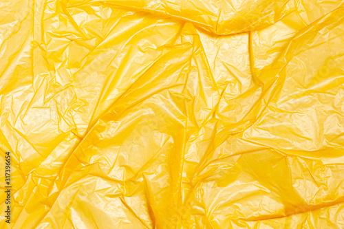 Surface of yellow wrinkled plastic bag. Texture of plastic film. Coating of polyethylene membrane. Abstract crumpled background.