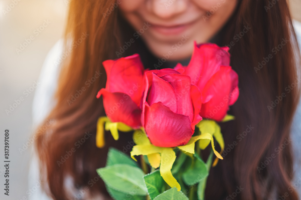Closeup image of a beautiful asian woman holding and smelling red roses flower with feeling happy on Valentine's day Closeup image of a beautiful asian woman holding and smelling red roses flower with feeling happy on Valentine's day