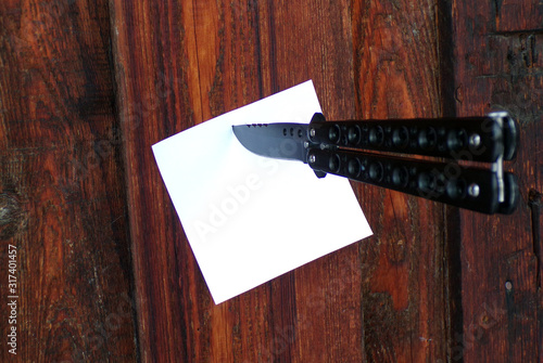 A message left by the robber on the door of the house. A knife stuck in the wall with a piece of paper. Copy space.