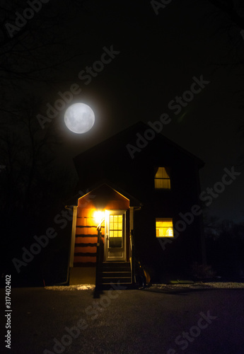 composite of full moon poking above house at night