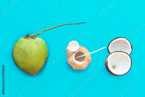 Set, composition, group of nuts, fruits coconuts: fresh green whole coconut, healthy cocktail, coconut milk, water, cut in half, two halves of coconut on blue background. Top view. Healthy vegan food