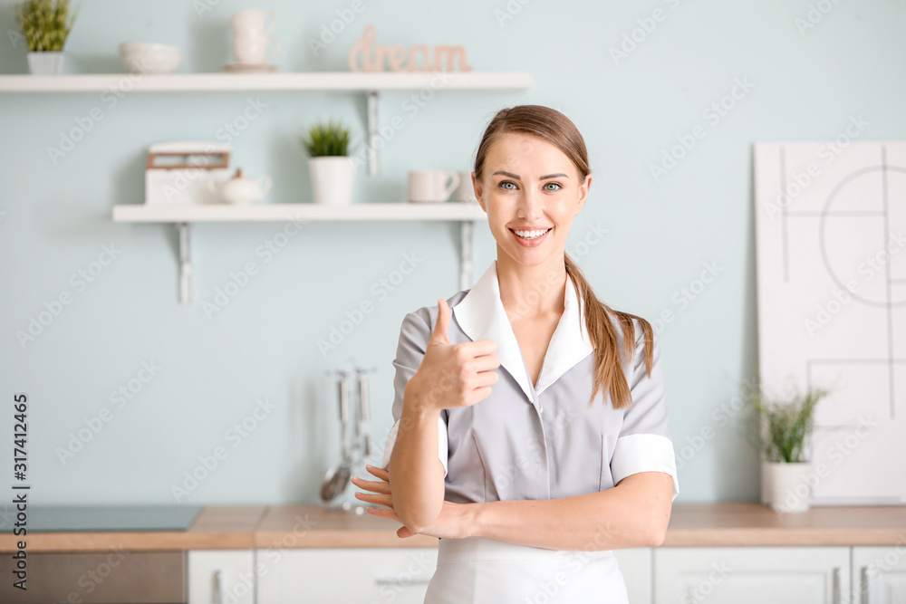Portrait of beautiful chambermaid showing thumb-up in kitchen Portrait of beautiful chambermaid showing thumb-up in kitchen