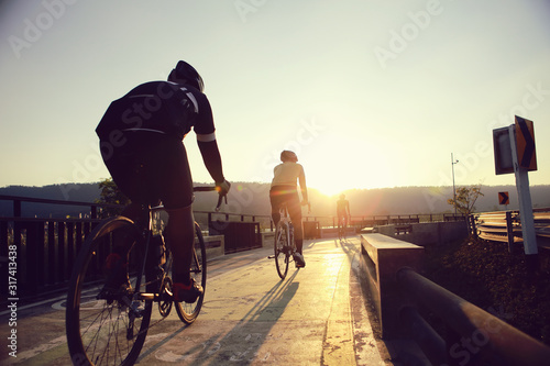 Cyclists are biking during the evening hours.