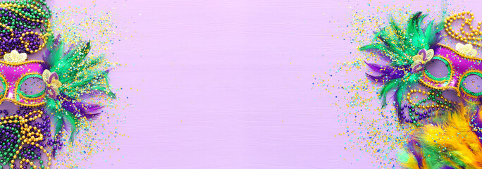 Holidays image of mardi gras masquarade, venetian mask and fan over purple background. view from above